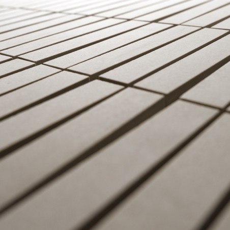 Des carreaux beiges rectangulaires sont posés à plat en rangées parallèles, créant un motif linéaire, entouré d'un arrière-plan 