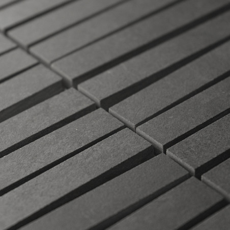Rechthoekige, donkergrijze tegels zijn uitgelijnd in parallelle rijen, waardoor een ritmisch patroon ontstaat. De tegels vormen 