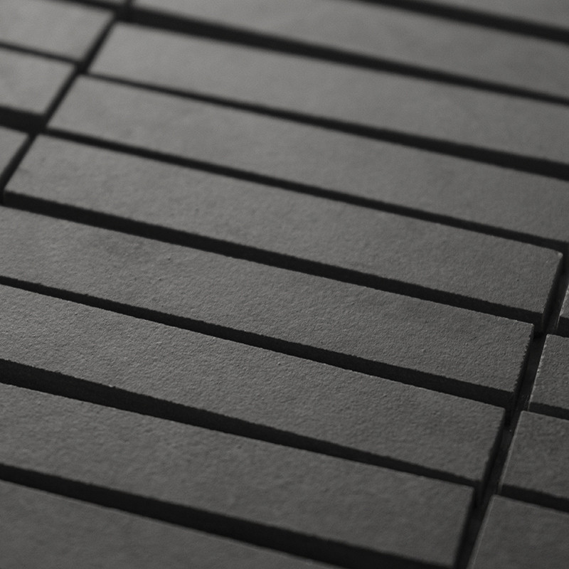 Les carreaux noirs rectangulaires sont disposés en quinconce, créant une texture géométrique subtile. Les carreaux présentent de