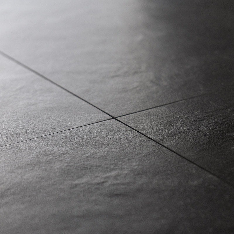 Les carreaux de pierre sombre, alignés selon un motif de grille, créent une surface lisse et mate avec une texture subtile, conf