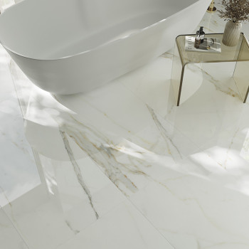 Een witmarmeren vloer met subtiele grijze en gouden aderen reflecteert het licht en omringt een strak, vrijstaand bad en een gla