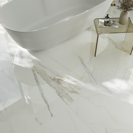 Een witmarmeren vloer met subtiele grijze en gouden aderen reflecteert het licht en omringt een strak, vrijstaand bad en een gla