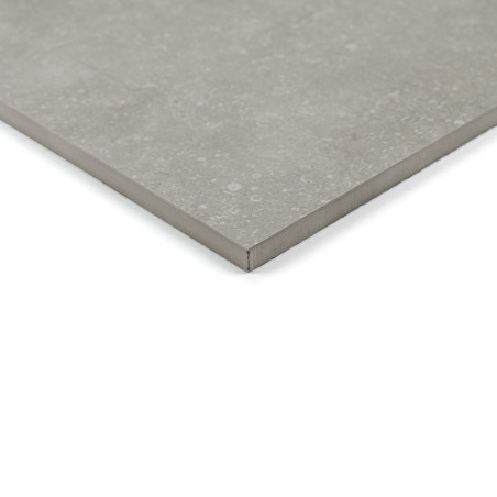 Eine glatte, graue Keramikfliese liegt auf einer weißen Oberfläche mit einem dezenten Sprenkelmuster. Die Ecke ist leicht erhöht