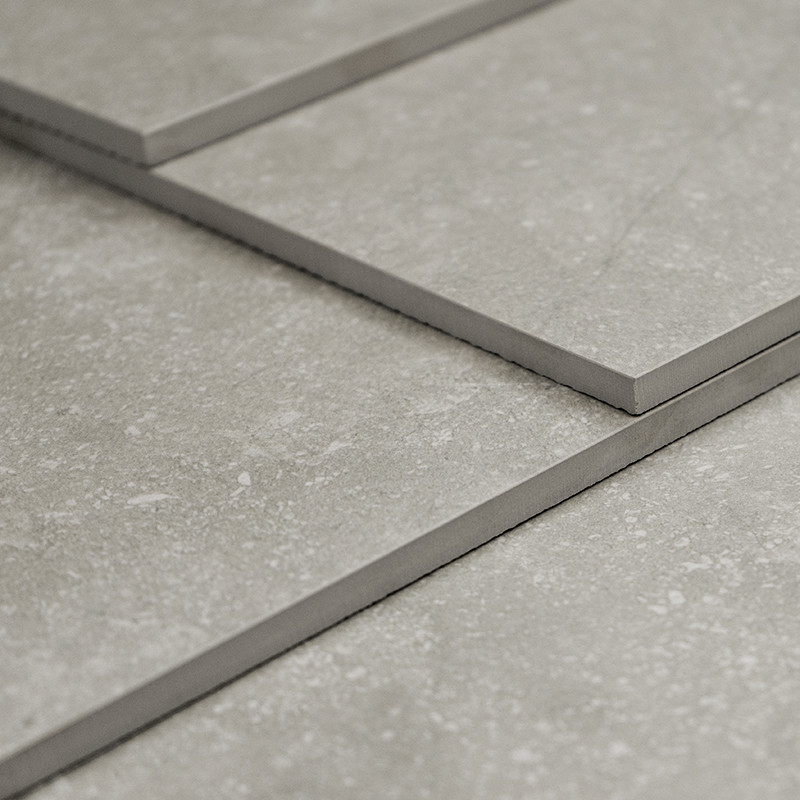 Rectangular tiles lie flat, slightly overlapping, showcasing a smooth texture with subtle speckled patterns in a neutral, light 