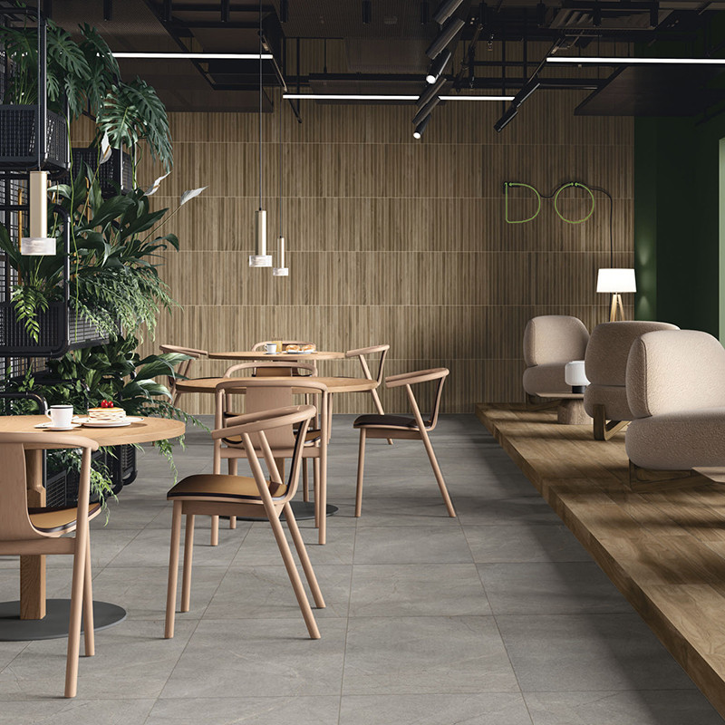 Holztische und -stühle auf hellgrauem Fliesenboden in einem modernen Café mit Pflanzen und gemischter Beleuchtung