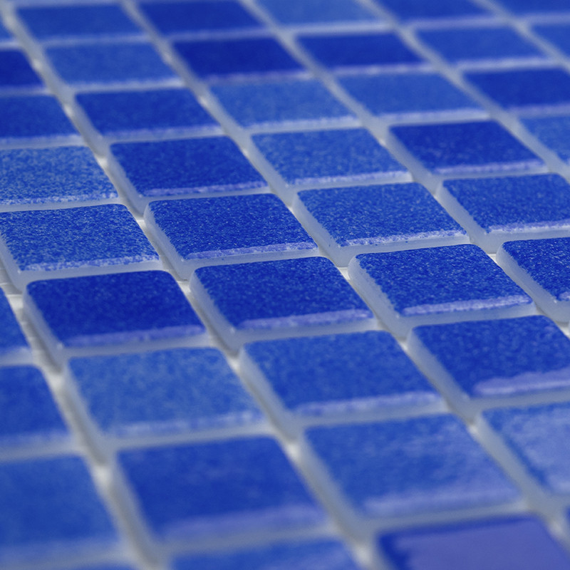 Blauwe glastegels vormen een vlak liggend raster en creëren een glinsterend oppervlak met lichtreflecties.