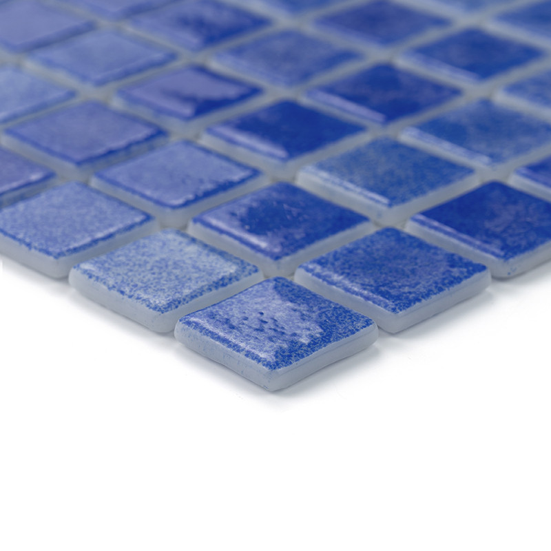 Los azulejos de vidrio azul forman un patrón de cuadrícula que refleja la luz sutilmente y se colocan sobre una superficie lisa.