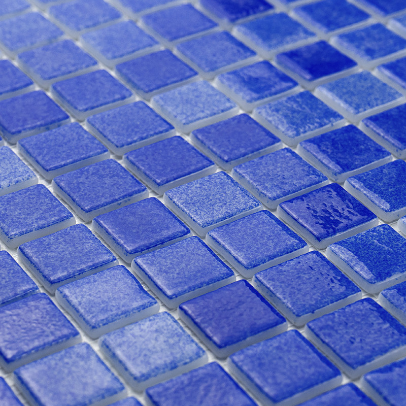 Geglazuurde blauwe glastegels zijn systematisch gerangschikt, waardoor een gestructureerd, reflecterend oppervlak in een rasterp