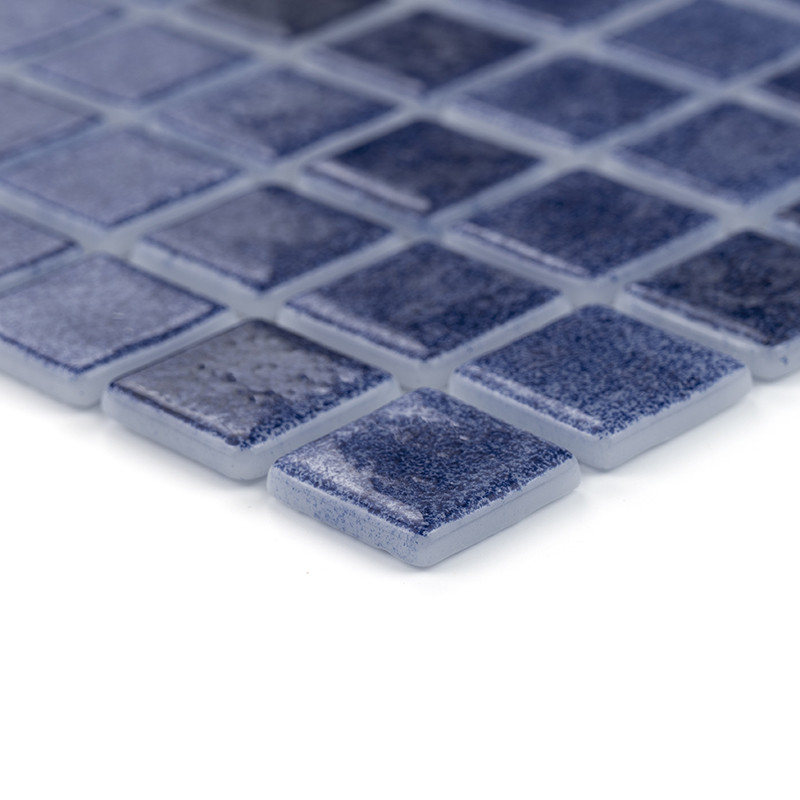 Blue square glass tiles sitting closely, forming a textured mosaic pattern on a flat surface.