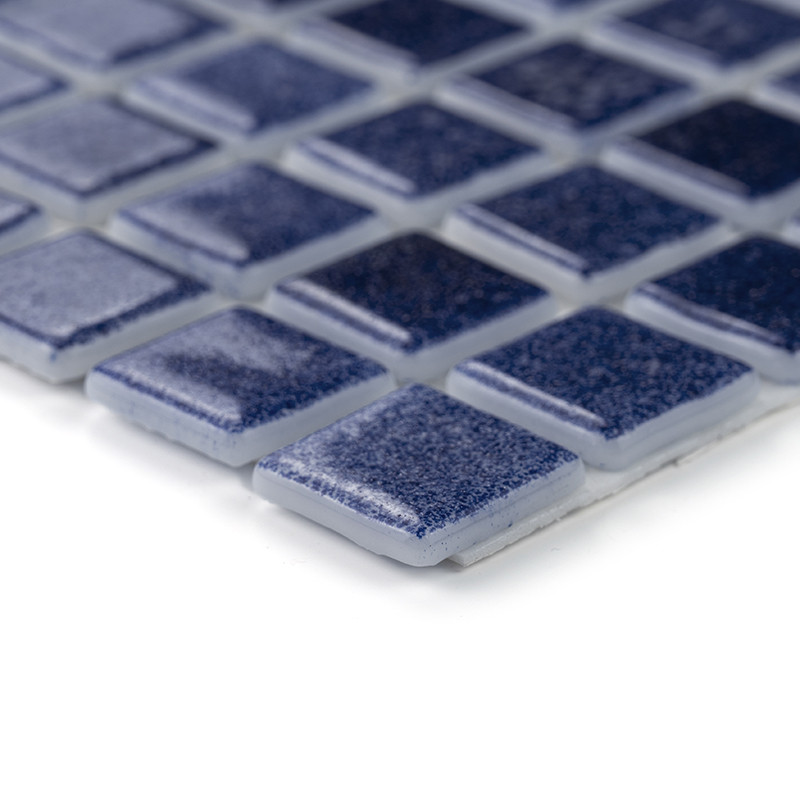 Ladrilhos de vidro azul colocados uniformemente, refletindo a luz, formam um elegante padrão de mosaico em uma superfície plana.