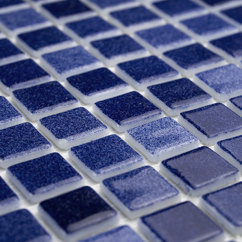Blaue Glasfliesen, die in einem Gittermuster angeordnet sind und Licht reflektieren, auf einer weißen Fugenbasis.