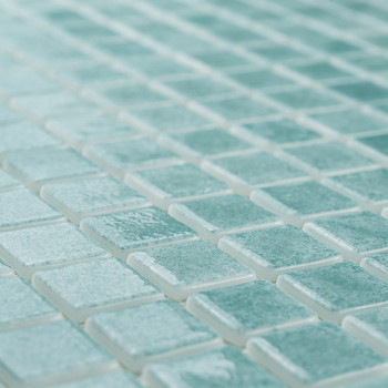 As telhas de vidro formam um mosaico, criando um padrão cintilante em uma superfície plana, com a luz realçando seu tom turquesa