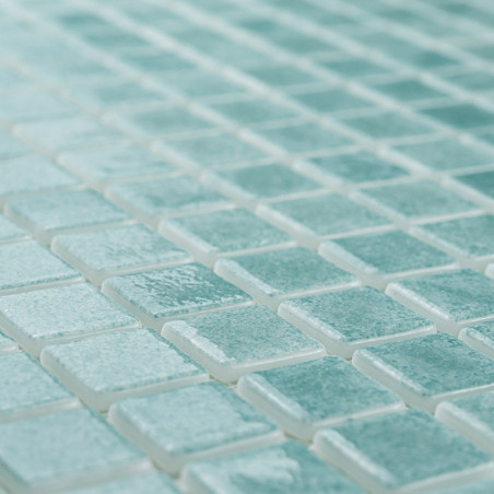 As telhas de vidro formam um mosaico, criando um padrão cintilante em uma superfície plana, com a luz realçando seu tom turquesa