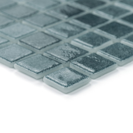 Ladrilhos de vidro quadrados dispostos ordenadamente, refletindo a luz sutilmente, em um padrão de grade contra um fundo branco 