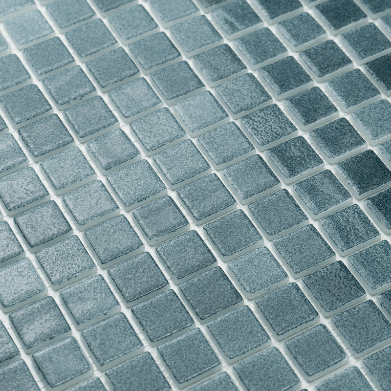 Los azulejos de vidrio cuadrados se alinean perfectamente, formando un patrón texturizado. Brillan sutilmente, en contraste con 
