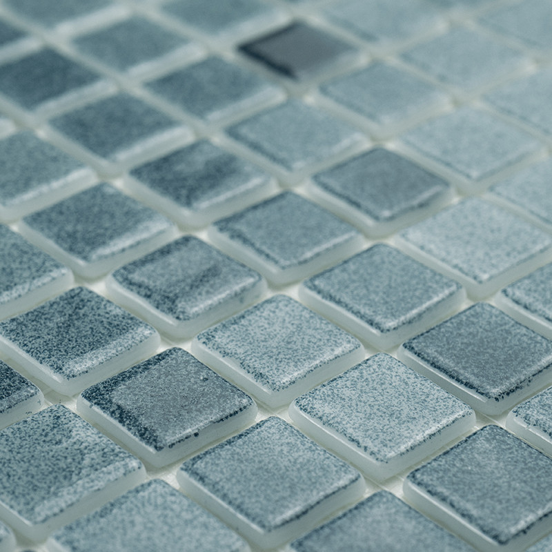 Los azulejos de vidrio cuadrados brillan sutilmente, reflejando la luz a través de una rejilla, creando un patrón de mosaico uni