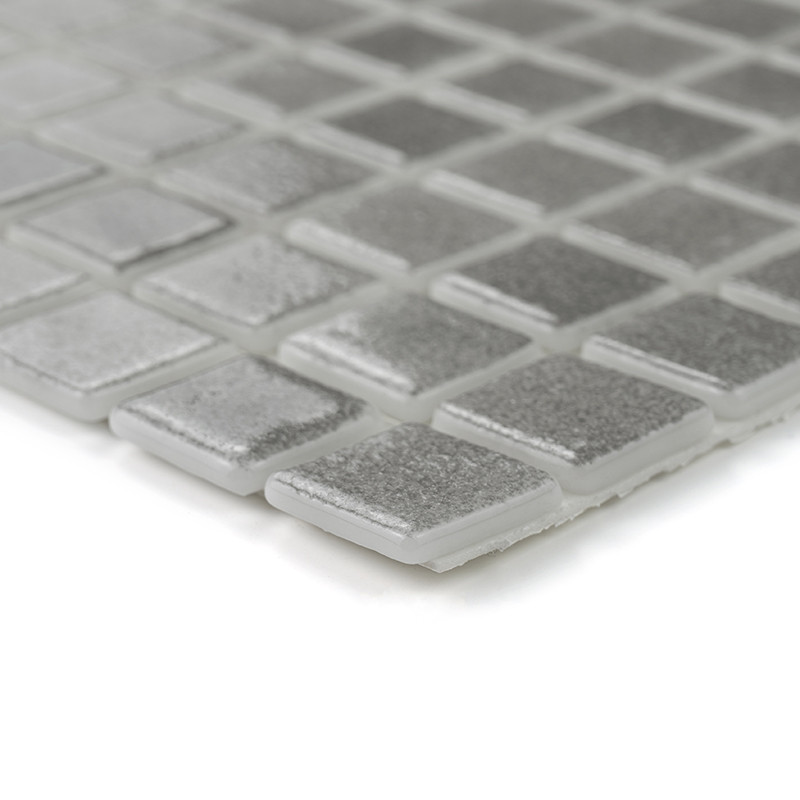 Square glass tiles form a shimmering silver mosaic, reflecting light, arranged in a grid pattern against a soft surface.