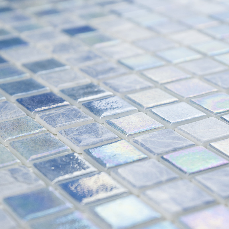 Schillernde Glasmosaikfliesen glitzern auf einer Oberfläche und zeigen in einem Gittermuster unterschiedliche Blau- und Weißtöne