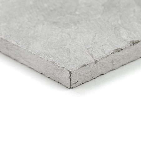 Una losa de piedra gris texturizada se encuentra sobre una superficie blanca, mostrando sus bordes ásperos y su parte superior l Una losa de piedra gris texturizada se encuentra sobre una superficie blanca, mostrando sus bordes ásperos y su parte superior l