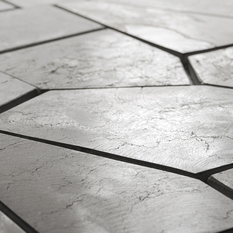 Stone tiles form an irregular, geometric pattern with visible cracks, situated on a smooth, neutral-toned surface.