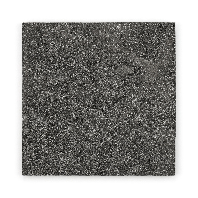 Quadratische Steinfliesen weisen eine gesprenkelte, dunkelgraue Textur auf und liegen auf einem schlichten weißen Hintergrund.