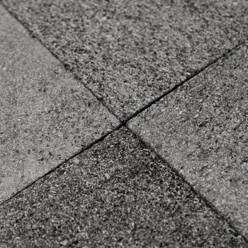 Graue Steinfliesen bilden auf einer ebenen Fläche ein strukturiertes, ineinandergreifendes Muster und sorgen so für einen einhei