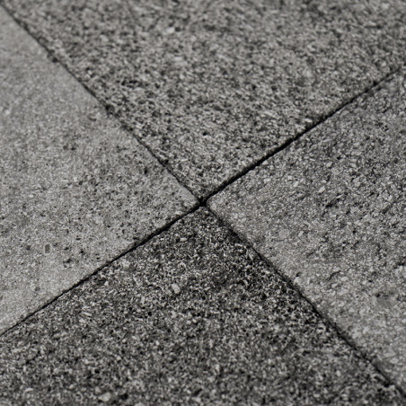 Graue Steinfliesen bilden auf einer ebenen Fläche ein strukturiertes, ineinandergreifendes Muster und sorgen so für einen einhei