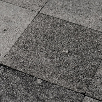 Graue Steinfliesen bilden eine strukturierte, unebene Oberfläche in einem geometrischen Muster und vermitteln eine natürliche, r