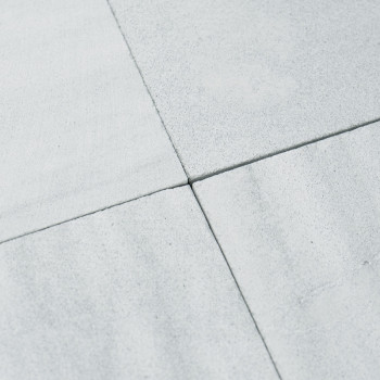 Uma placa informativa exibe texto em seis idiomas, explicando o tom natural e as variações de tamanho dos ladrilhos de pedra.