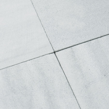 Uma placa informativa exibe texto em seis idiomas, explicando o tom natural e as variações de tamanho dos ladrilhos de pedra.