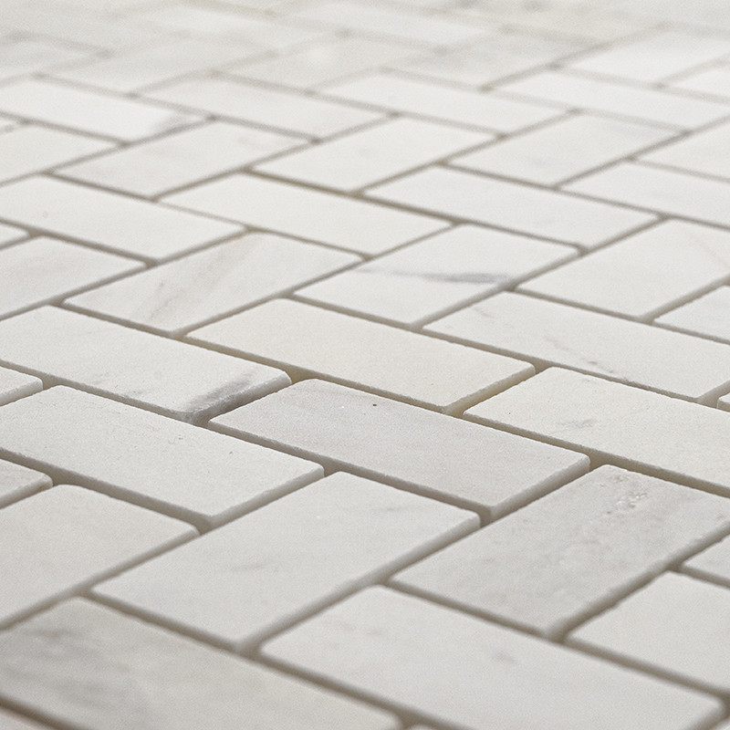 Los azulejos de piedra rectangulares forman un patrón en espiga, creando una superficie uniforme con tonos grises claros y blanc