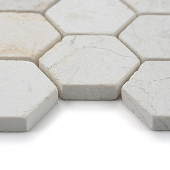Sechseckige Steinfliesen liegen eng aneinander und zeigen eine strukturierte, cremefarbene Oberfläche in einem hellen, minimalis