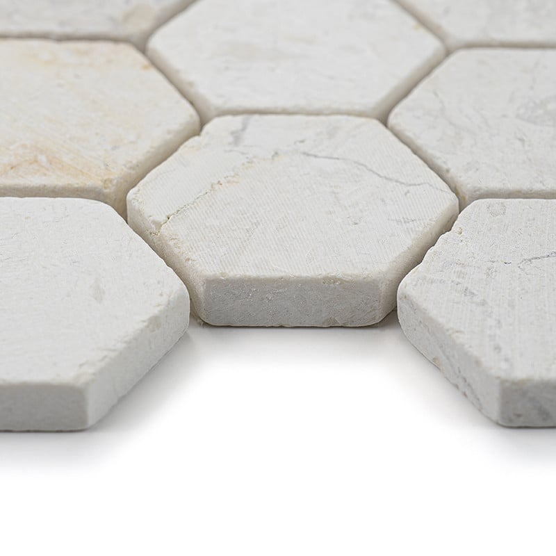 Les carreaux de pierre hexagonaux sont étroitement alignés, affichant une surface texturée blanc cassé dans un espace lumineux e