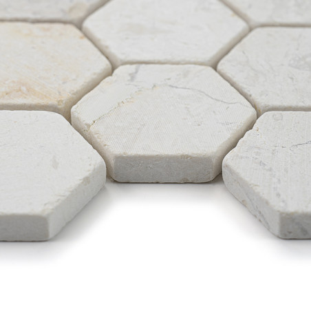 Zeshoekige stenen tegels liggen dicht bij elkaar en laten een gestructureerd, gebroken wit oppervlak zien in een heldere, minima