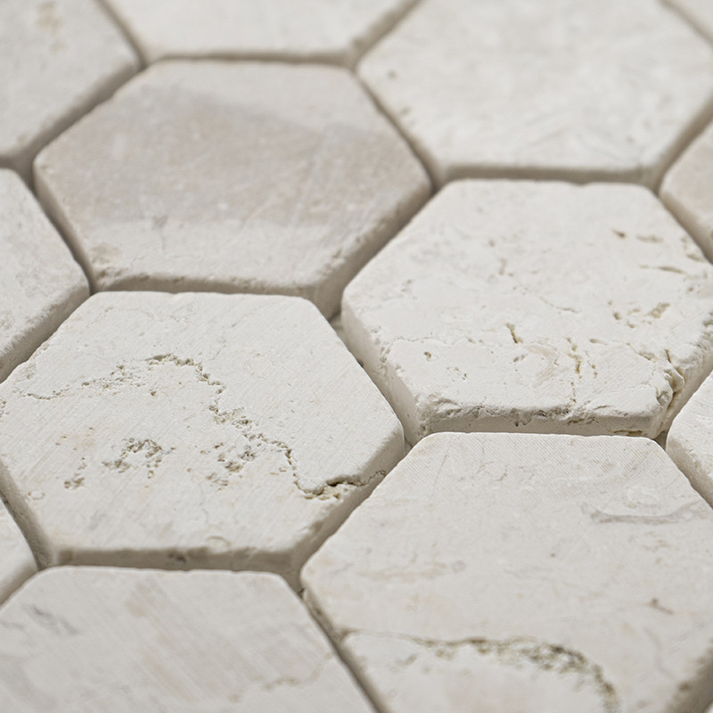 Ladrilhos de pedra hexagonais se interligam estreitamente, criando uma superfície branca texturizada e perfeita em um padrão geo