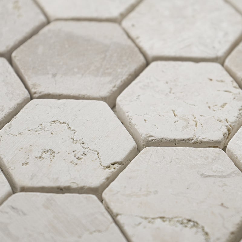 Les carreaux de pierre hexagonaux forment un motif texturé, avec des surfaces blanches rugueuses et de subtiles veines grises, é