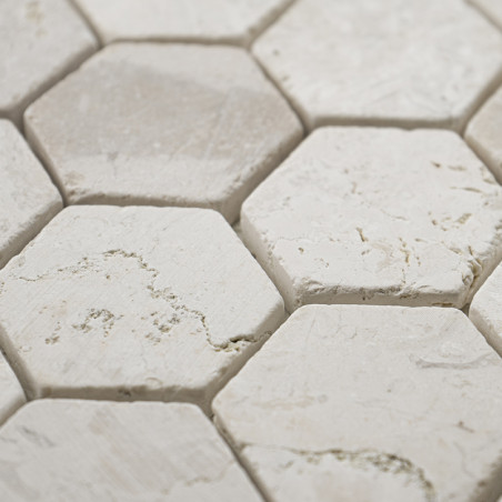 Zeshoekige steentegels vormen een structuurpatroon, met ruwe witte oppervlakken en subtiele grijze aderen, dicht bij elkaar.