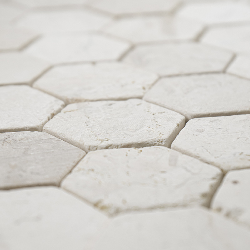 Los azulejos de piedra hexagonales se entrelazan estrechamente, creando una superficie blanca texturizada y sin costuras en un p