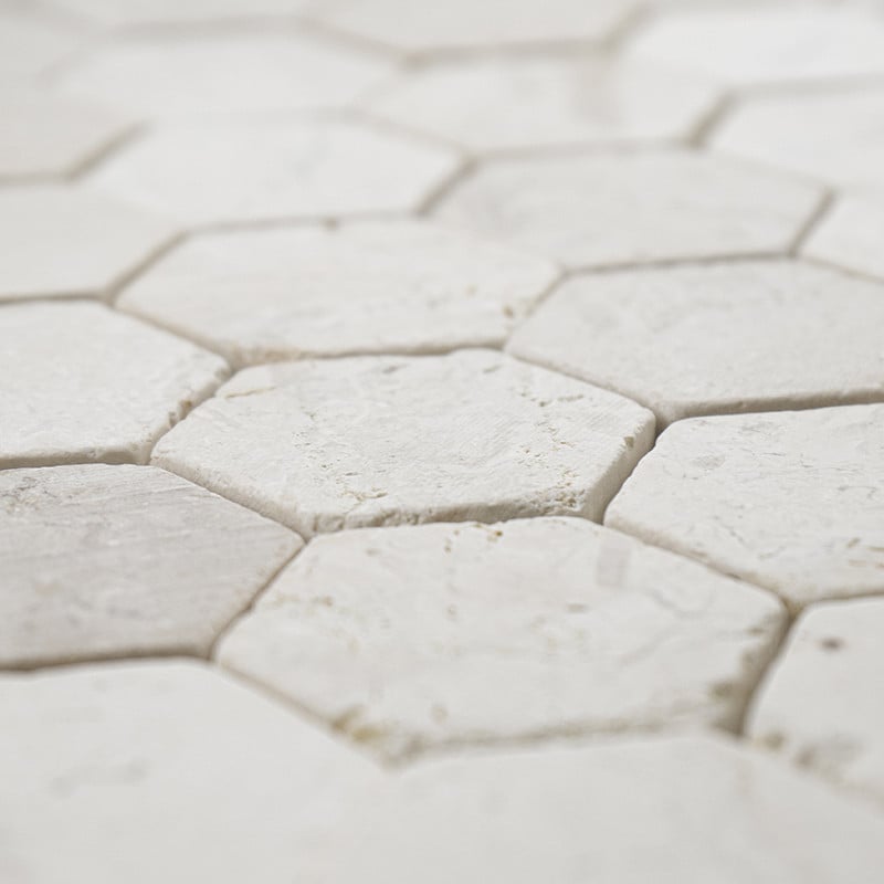 Les carreaux de pierre hexagonaux s'emboîtent étroitement, créant une surface blanche texturée et homogène dans un motif géométr