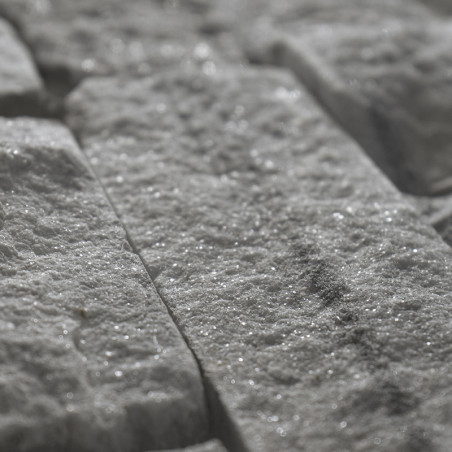 Rough, rectangular stone tiles reflect light, creating a sparkling effect in a close-up view, laid in an interlocking pattern.