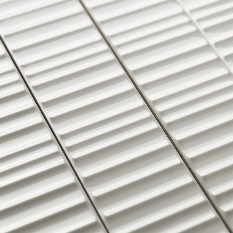 Weiße Keramikfliesen weisen erhabene lineare Rippen auf, die parallel angeordnet sind und ein strukturiertes Muster erzeugen. Si
