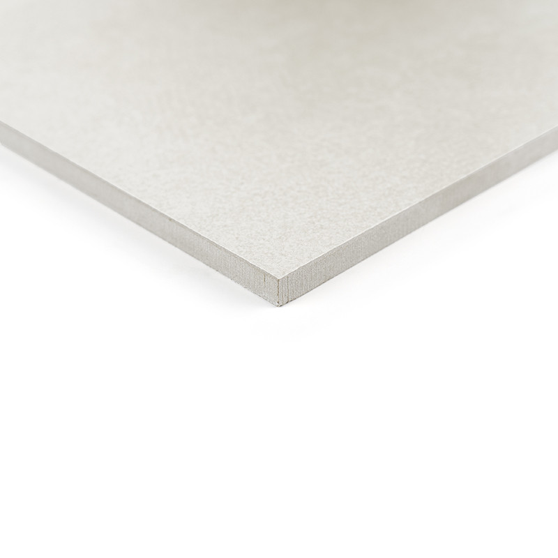 A square, flat, light gray tile sits on a white surface, showcasing its smooth texture and precise edges in a minimalistic setti