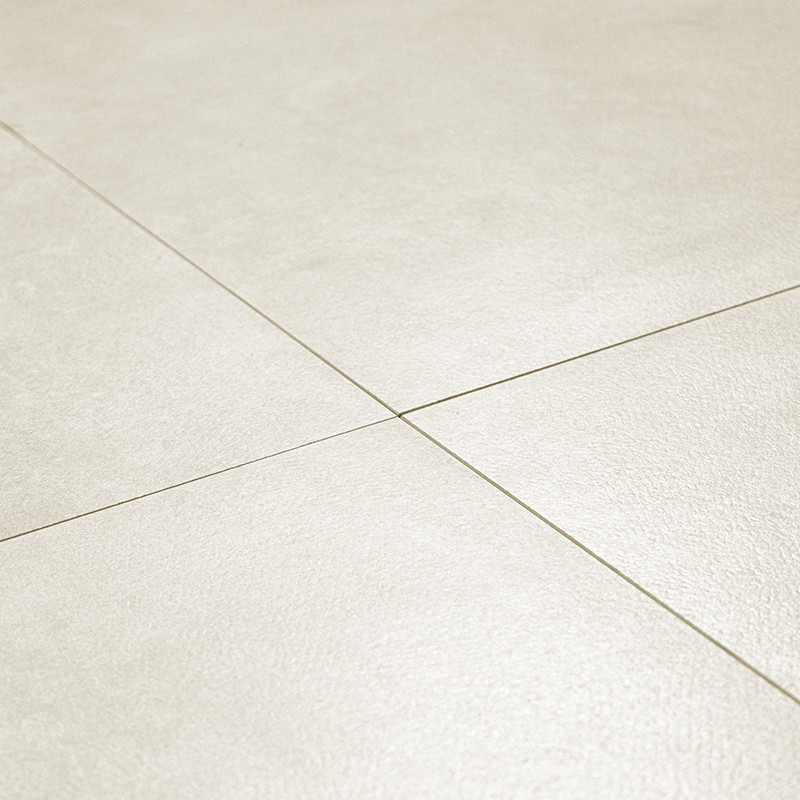 Beige ceramic tiles form a grid pattern, joined by thin grout lines, creating a smooth, uniform floor surface in a bright room.