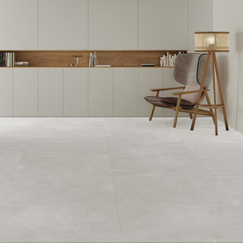 Une chambre minimaliste présente de grands carreaux de sol gris clair. Une chaise en bois avec des coussins et un lampadaire rep