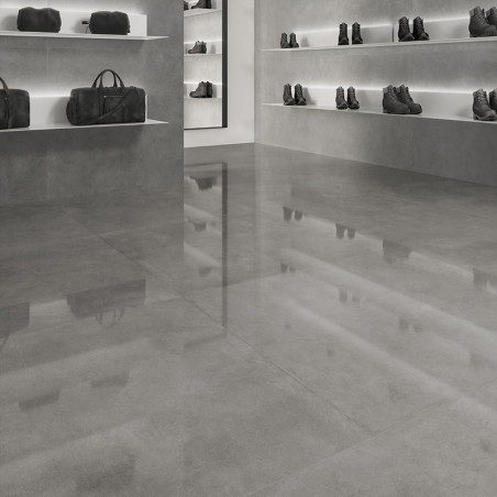 Der graue Fliesenboden glänzt und spiegelt ein Einzelhandelsumfeld mit Regalen mit dunklen Ledertaschen und Stiefeln vor grauen 