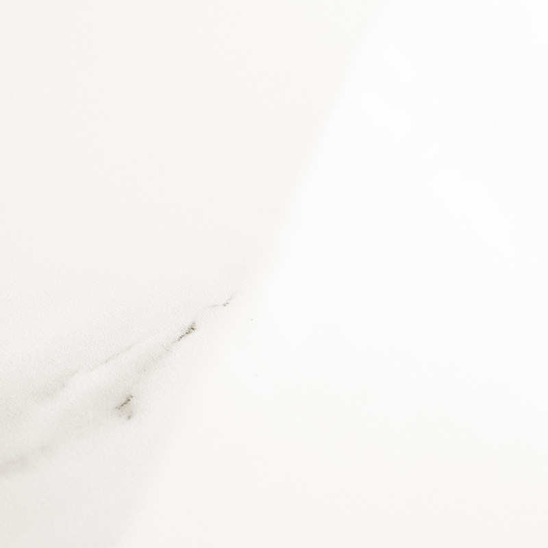 Un azulejo blanco, con sutiles vetas grises, descansa en una iluminación suave, creando una apariencia elegante y minimalista ad
