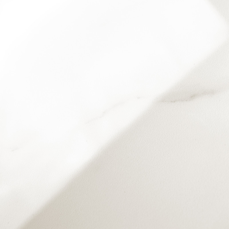Un carreau de marbre blanc lisse avec de subtiles veines grises s'étend en diagonale sur une surface plane et bien éclairée, don