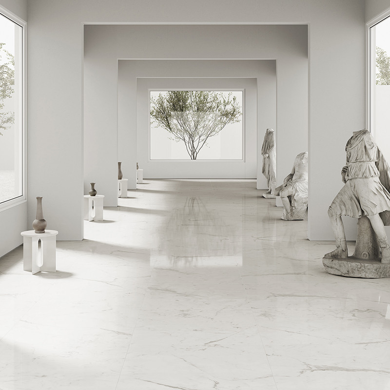 Marble statues stand in an elegant, light-filled corridor, each positioned on pedestals beside smooth, reflective floors. Large 