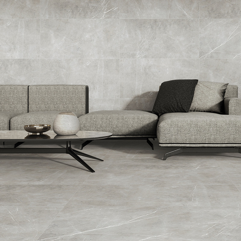 El suelo de azulejos grises se extiende a lo largo de una sala de estar minimalista con un moderno sofá gris y una elegante mesa