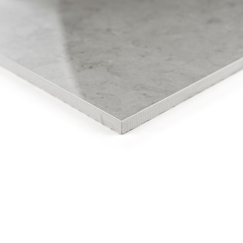 A smooth, gray ceramic tile in the corner position, showcasing its polished surface and thin profile, lies on a white background